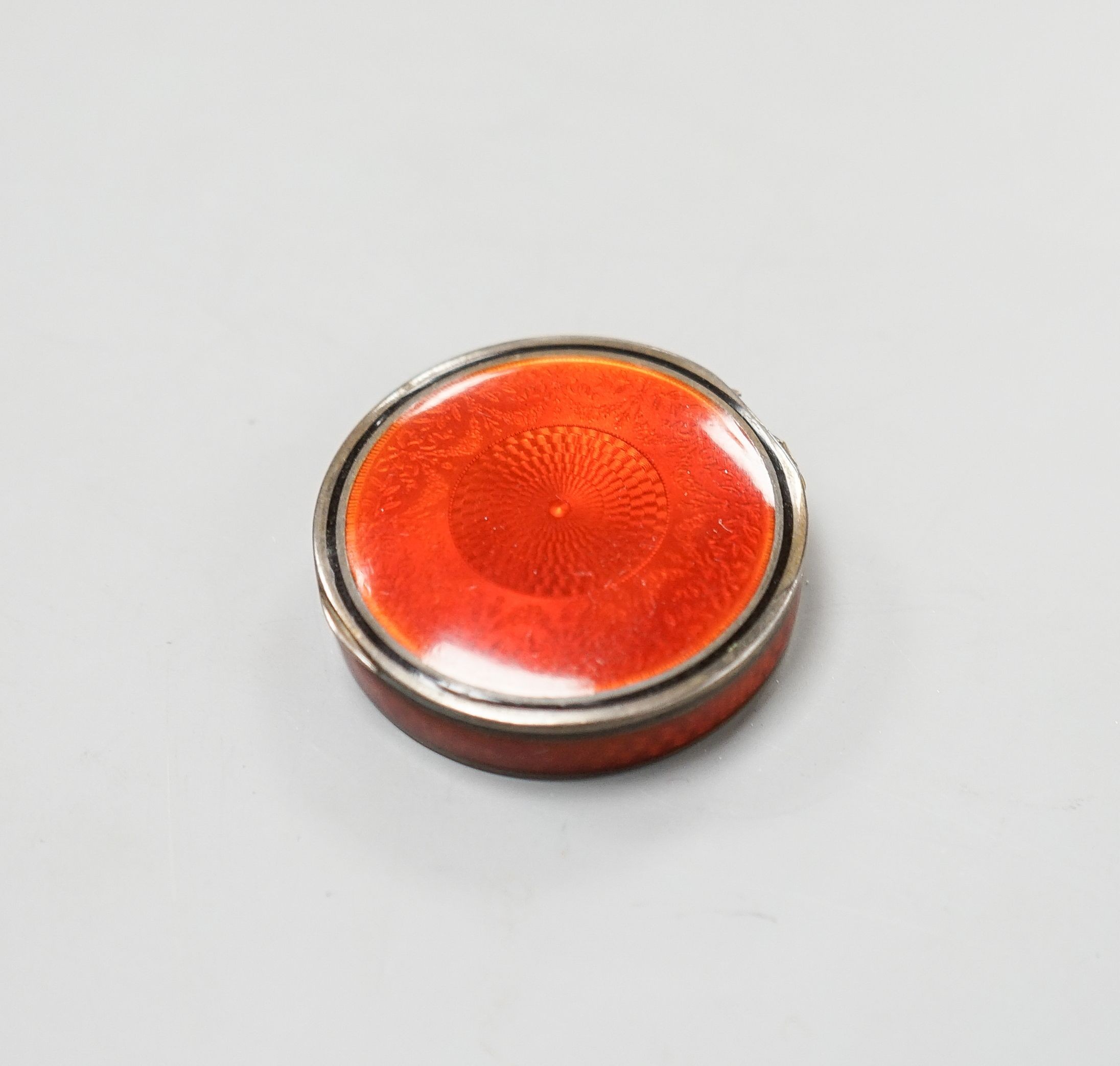 An early 20th century French engine turned white metal and red enamel circular pill box, 40mm.